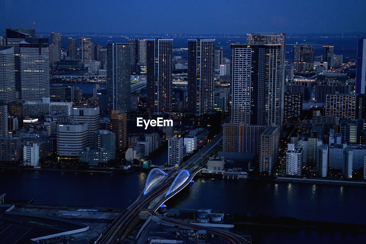 AERIAL VIEW OF ILLUMINATED CITY BUILDINGS AGAINST SKY