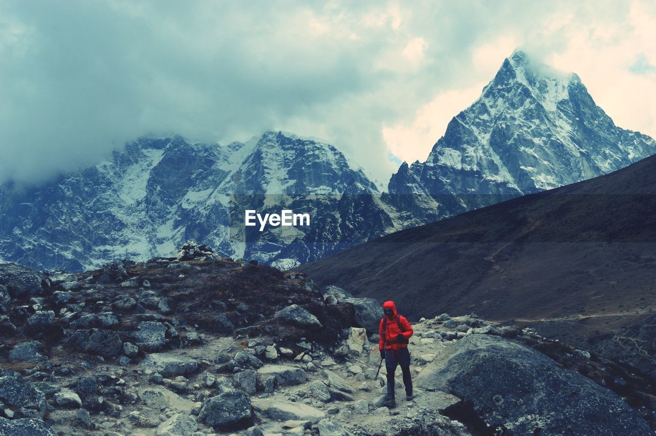 Full length of person trekking on snowcapped mountain against sky