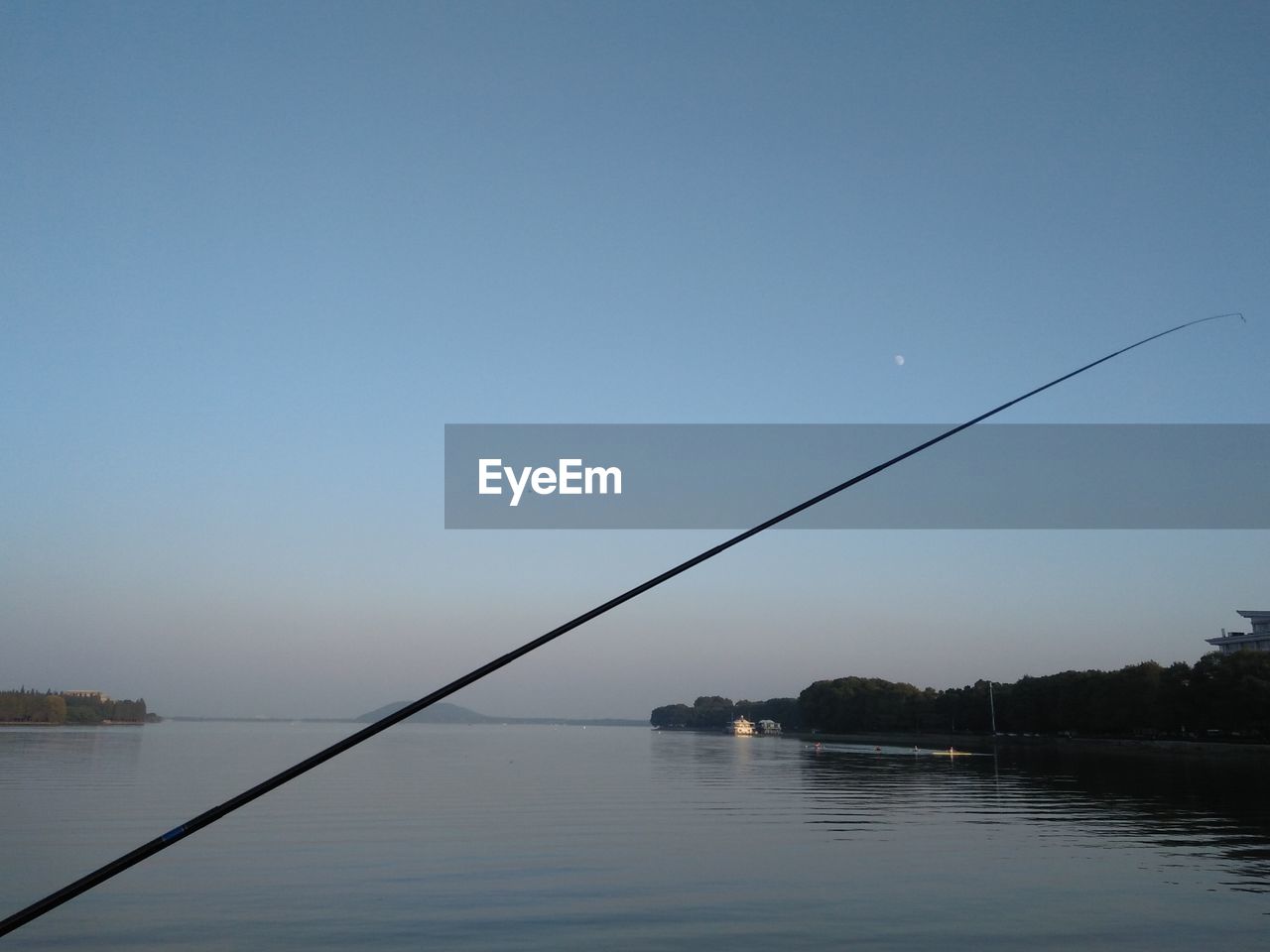 FISHING ROD OVER LAKE AGAINST SKY