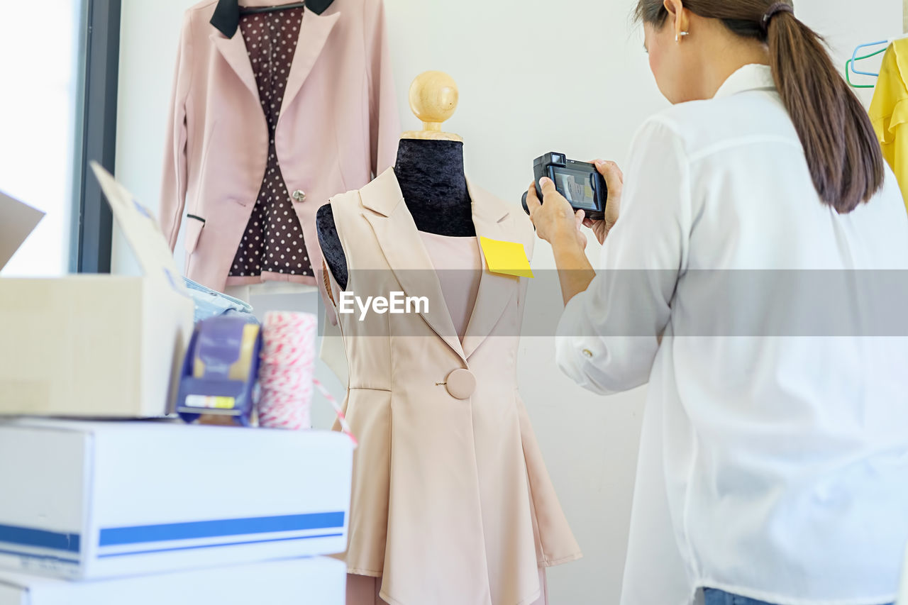 Fashion designer photographing dress in workshop