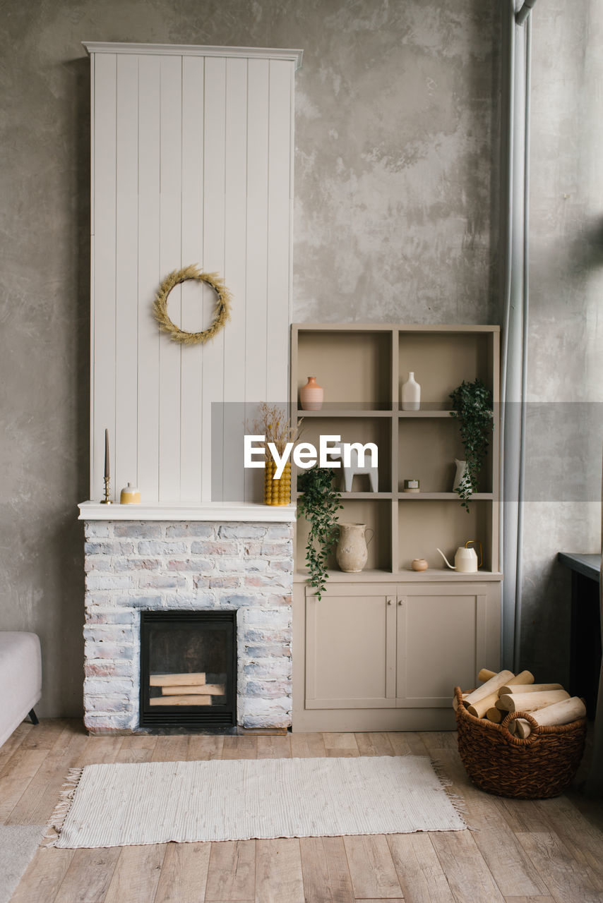 Scandinavian interior of the living room with a fireplace and an open wardrobe with shelves