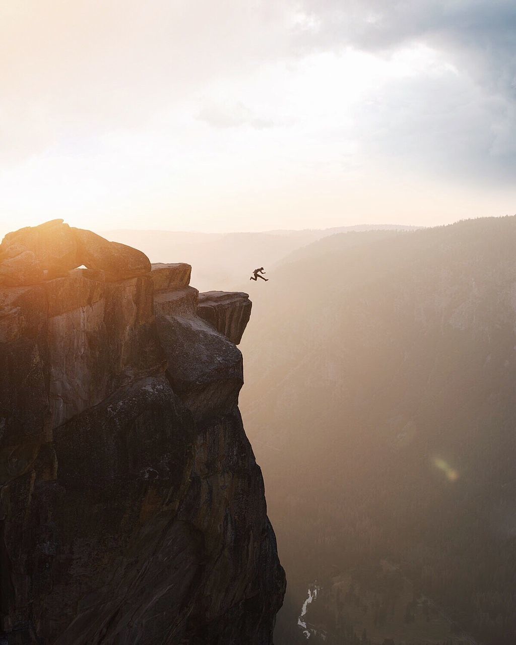 Distant man jumping from the top of a mountain