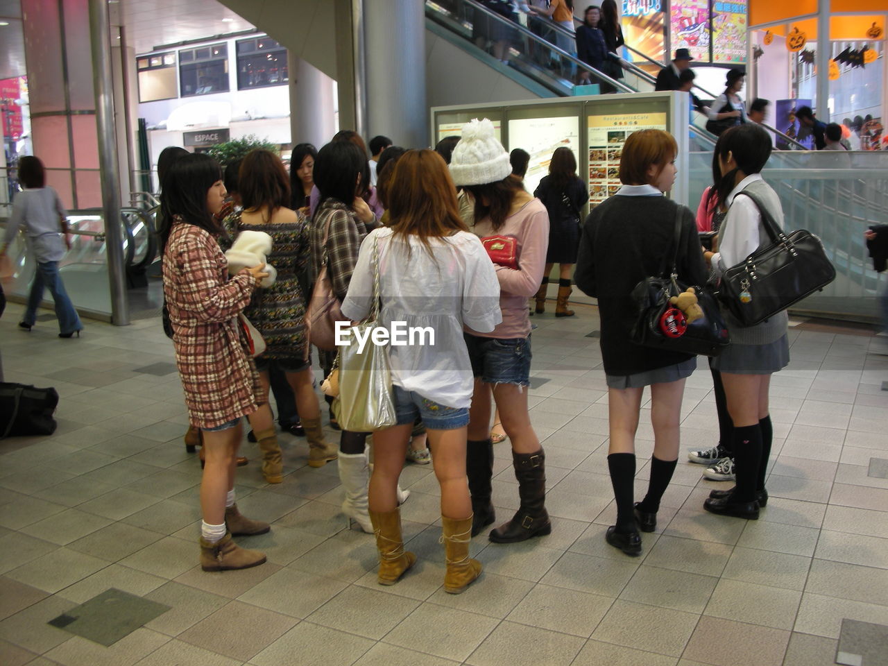 REAR VIEW OF PEOPLE WALKING ON TILED FLOOR IN SHOPPING MALL