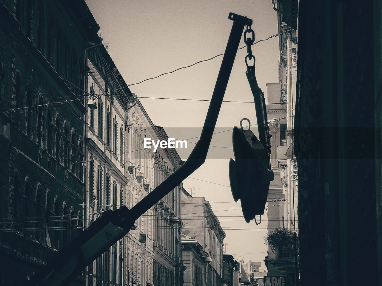 LOW ANGLE VIEW OF SILHOUETTE ROPE HANGING ON STREET BY BUILDINGS