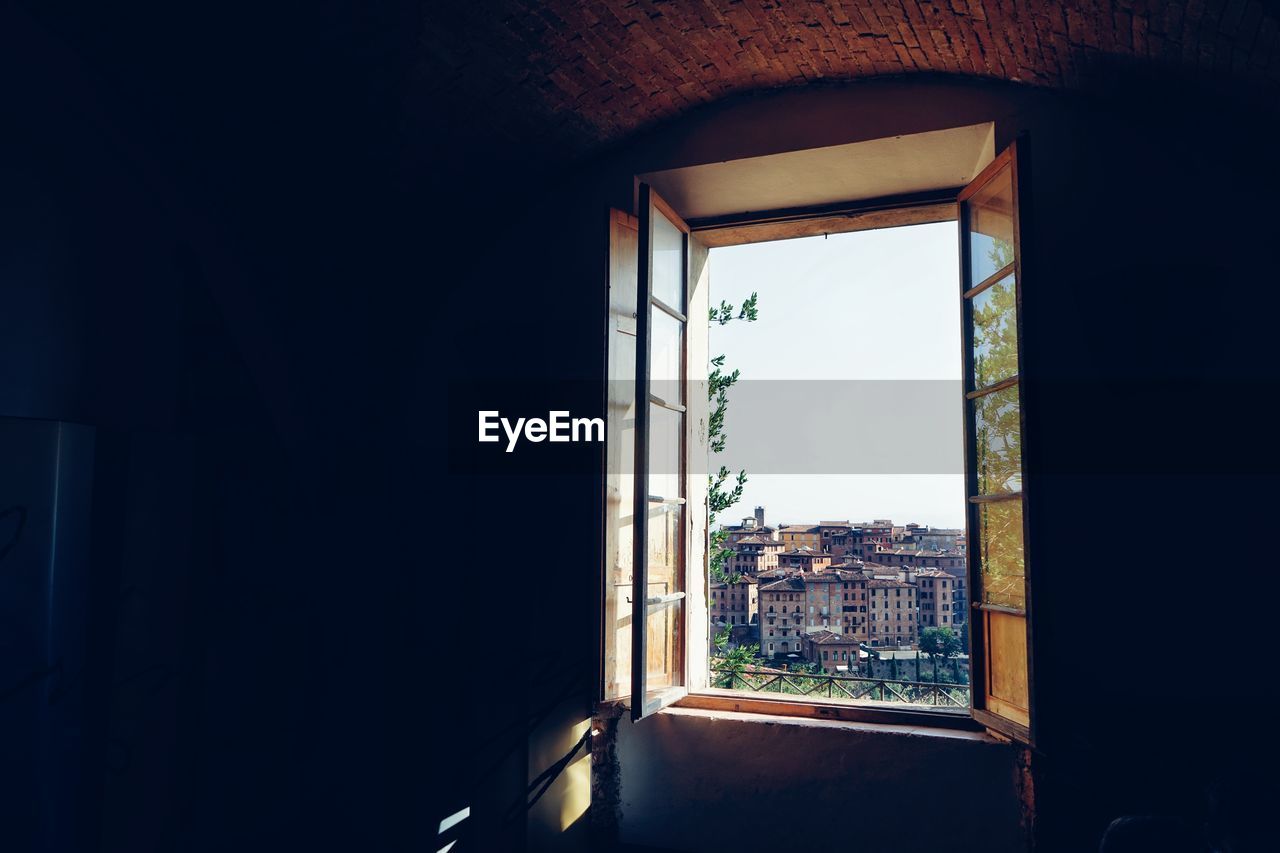 Buildings against sky seen through window