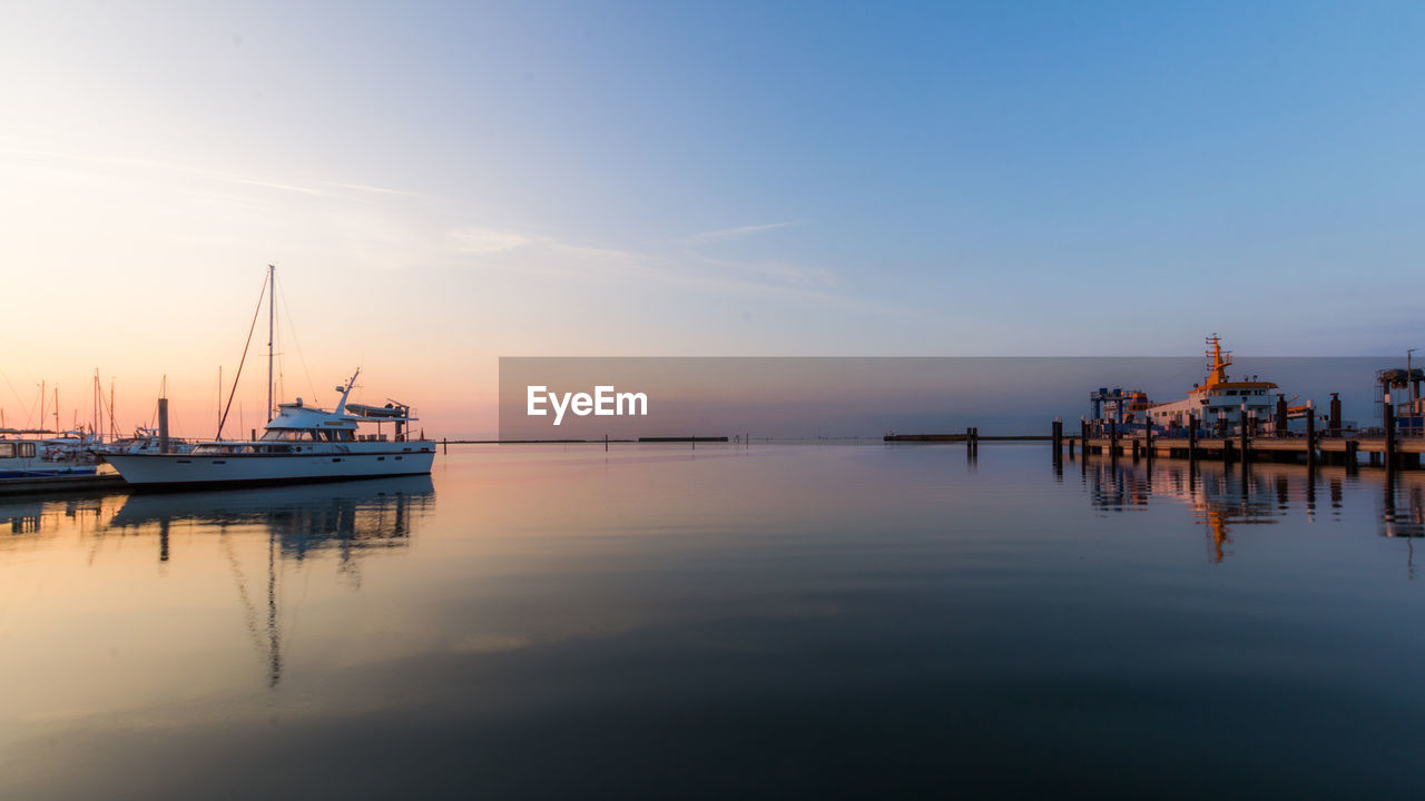SAILBOATS IN SEA AT SUNSET