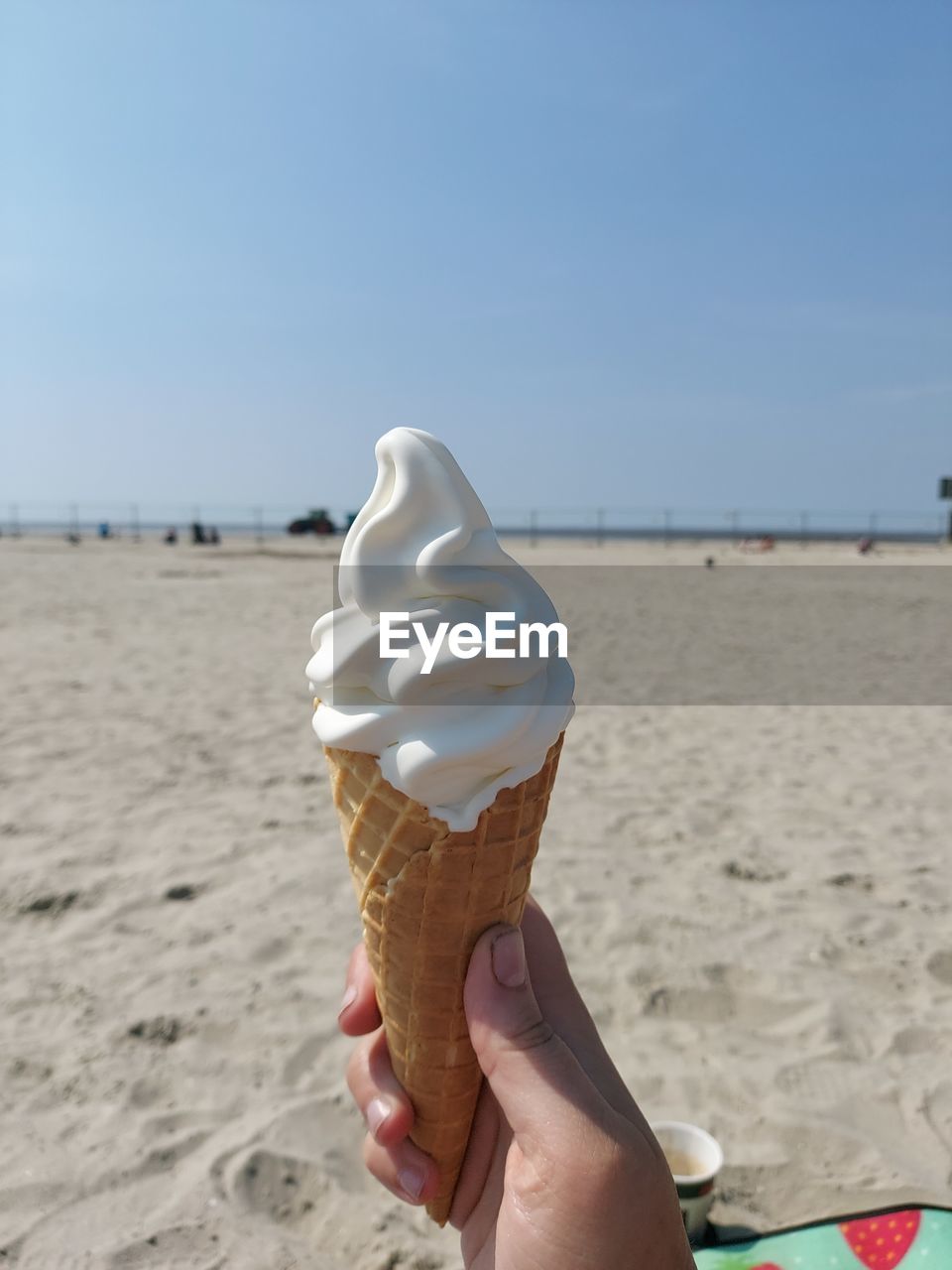 MIDSECTION OF WOMAN HOLDING ICE CREAM ON BEACH