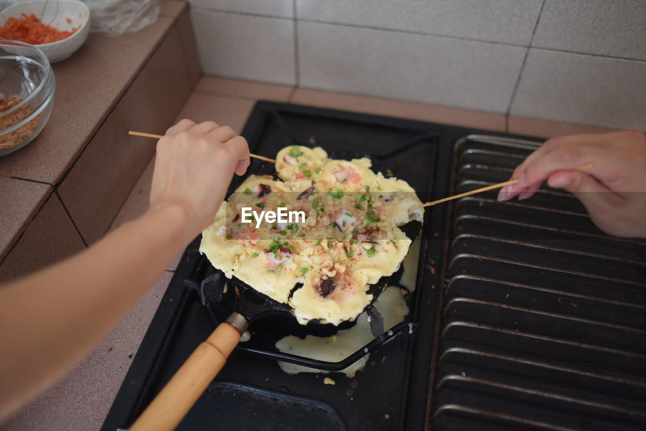 Cropped hands of people cooking food on stove in kitchen