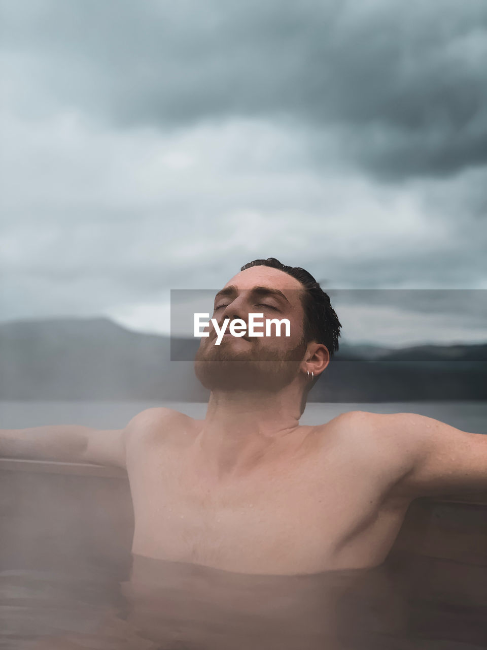 Portrait of young man in water against sky