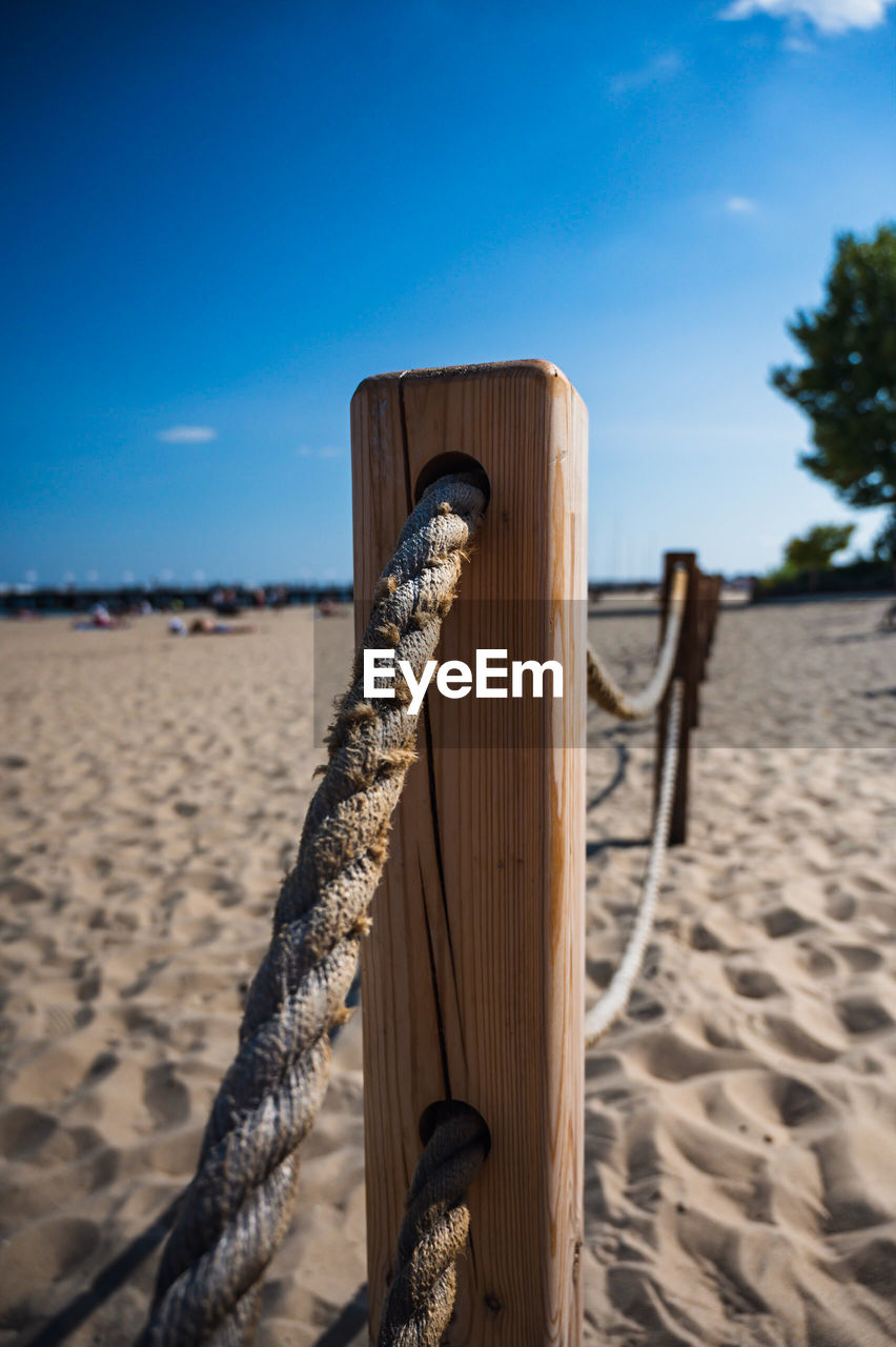 CLOSE-UP OF WOODEN POSTS ON BEACH