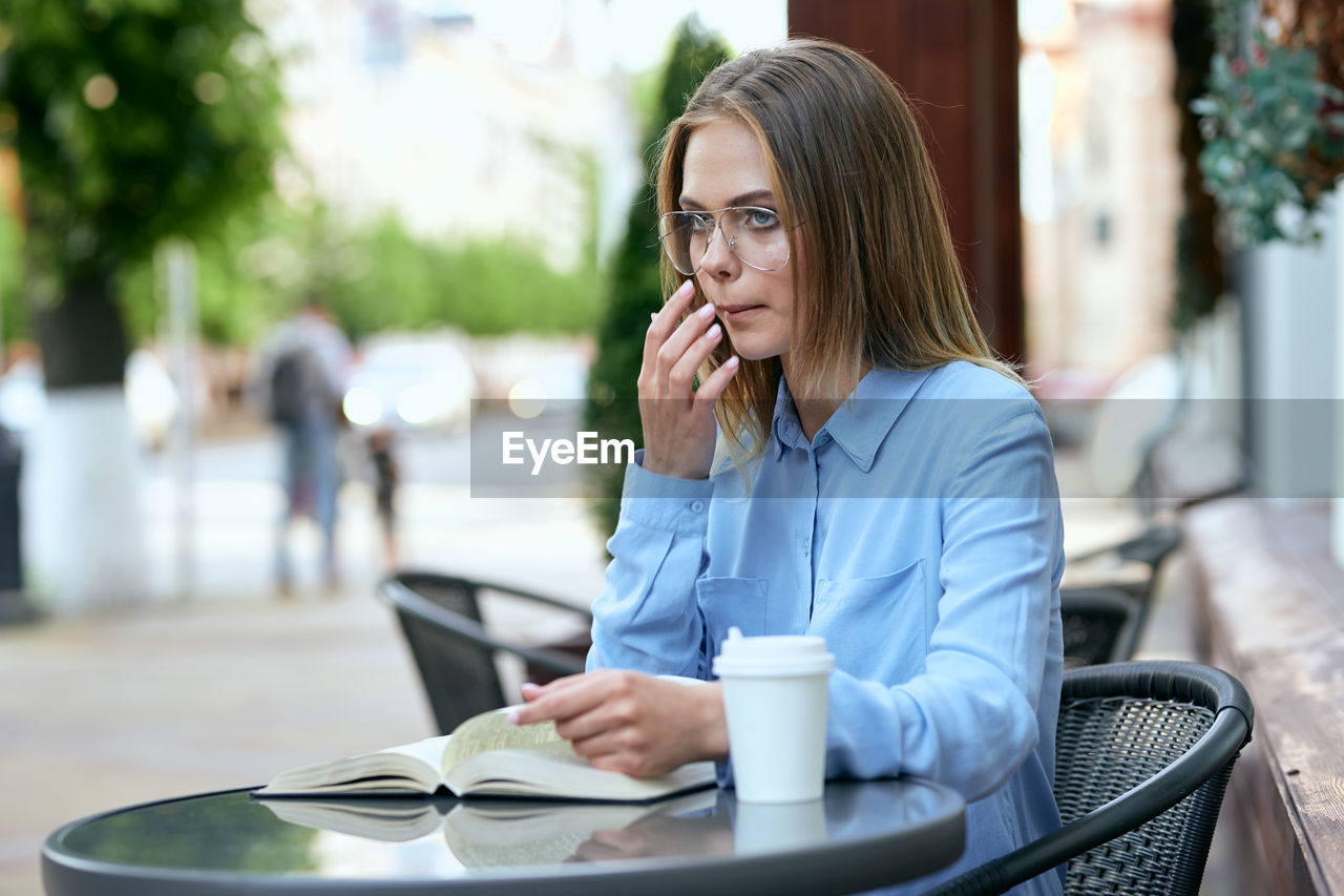 young woman using mobile phone while sitting on table