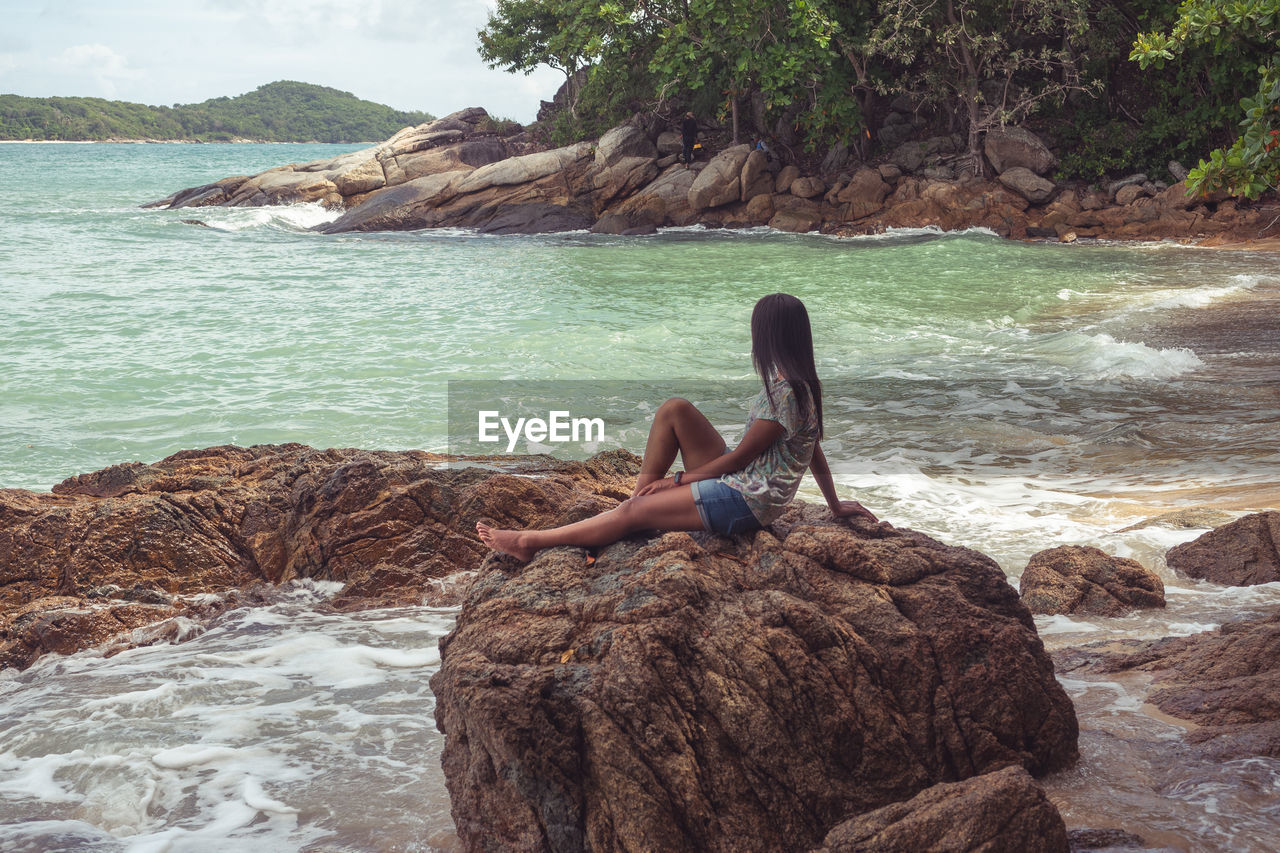 Man sitting on rock at sea shore