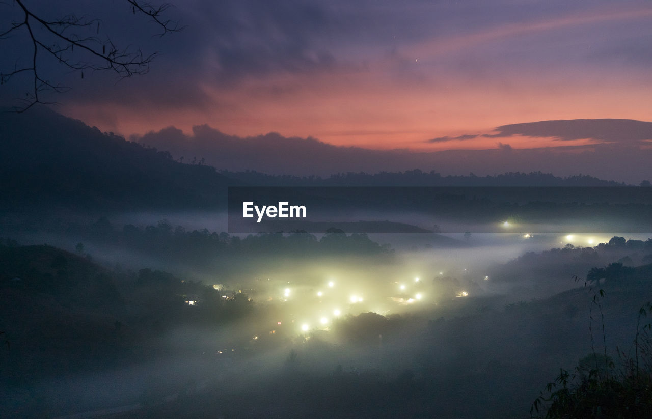 SCENIC VIEW OF ILLUMINATED MOUNTAINS AGAINST SKY AT SUNSET