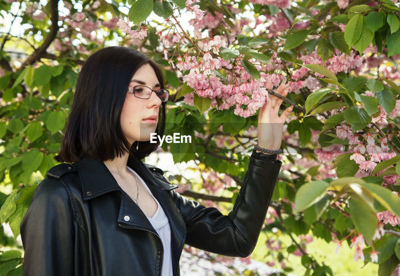 Beautiful young woman standing by flowering plants