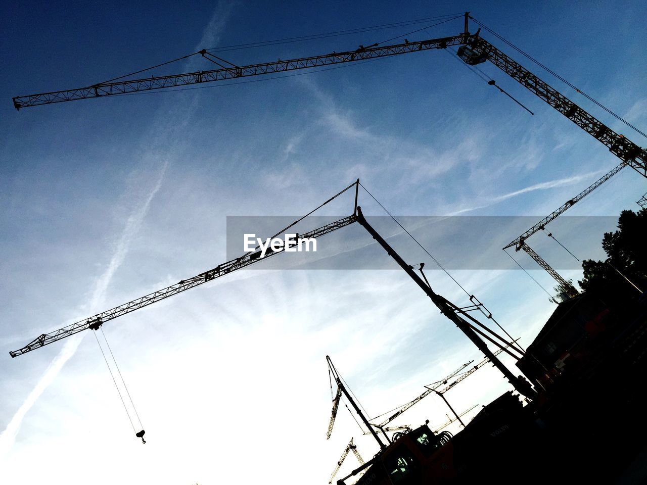 Low angle view of cranes against blue sky