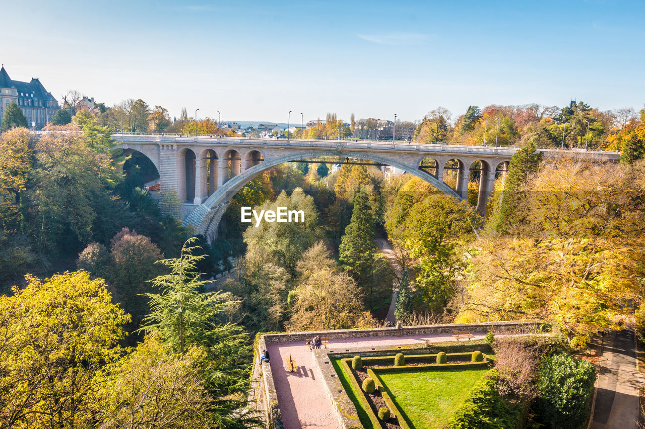 Arch bridge over river against sky during autumn