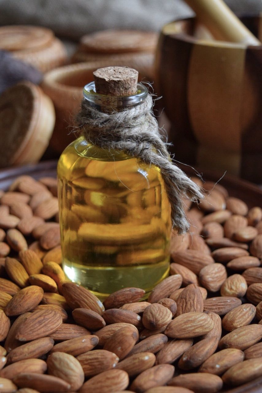 Close-up of liquid in bottle on almonds at table