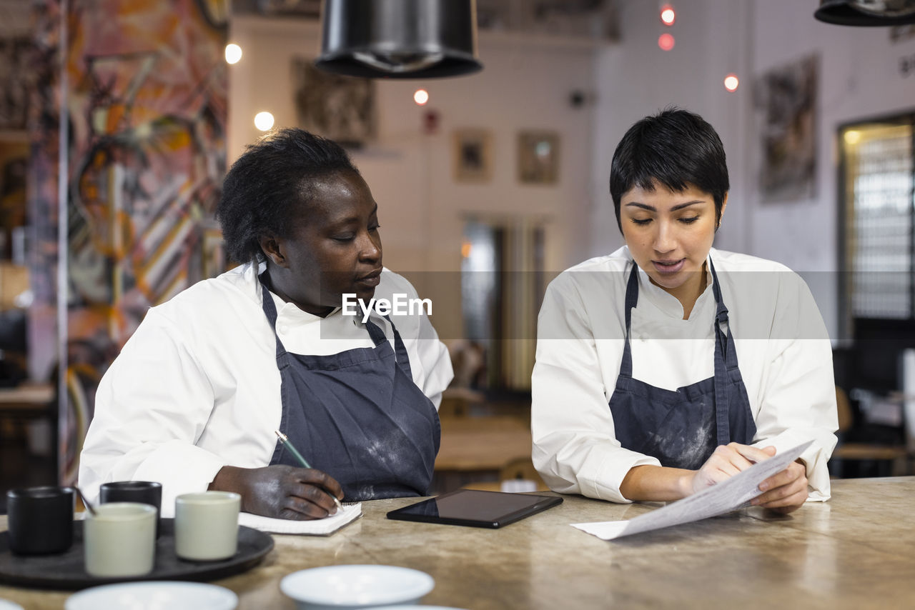 Female colleagues discussing menu card at table in restaurant