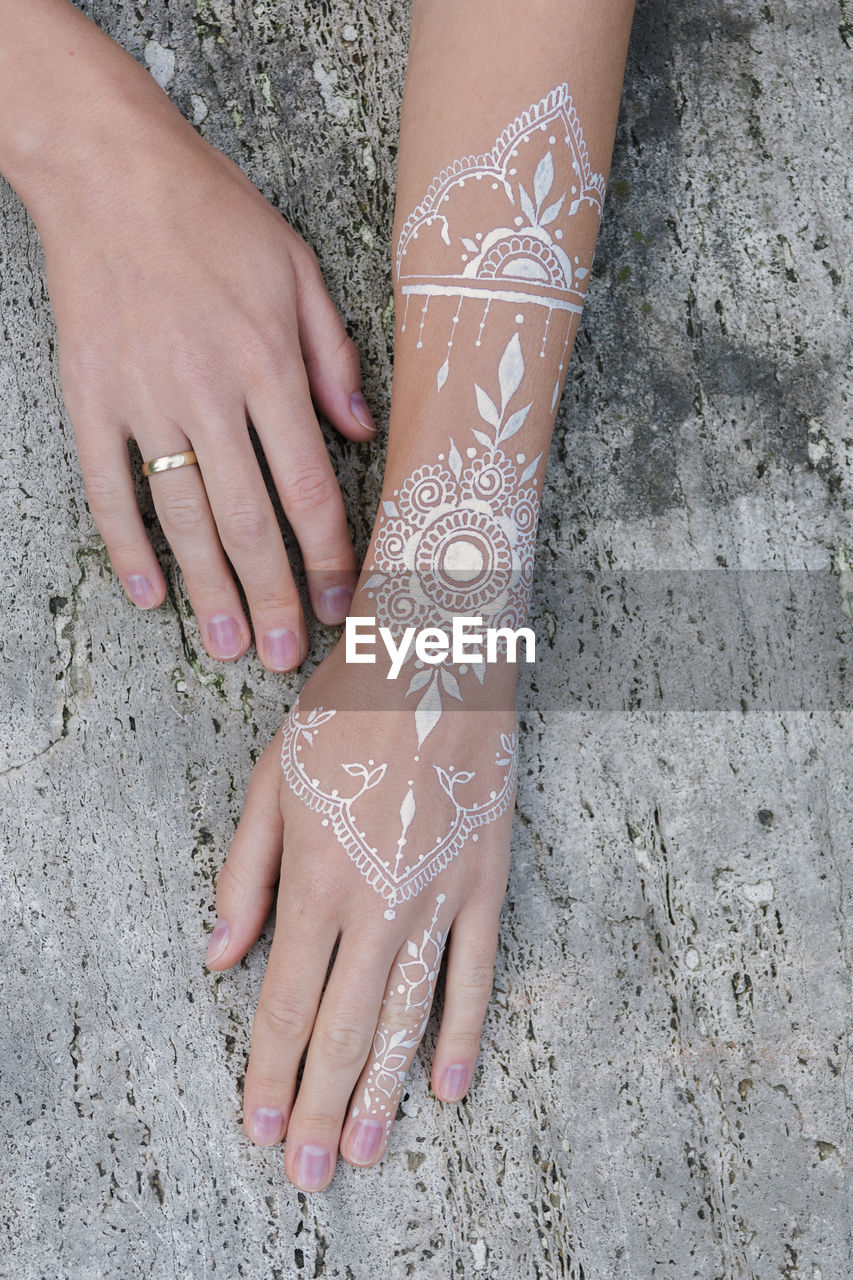 Cropped hands with henna tattoo on wood