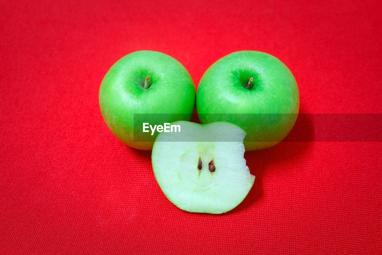 CLOSE-UP OF APPLES ON RED SURFACE