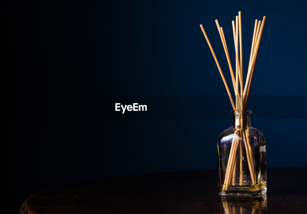 Close-up of incenses in glass jar against black background