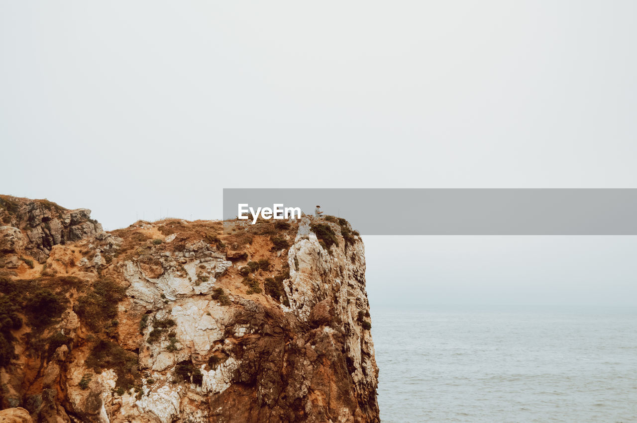 Rock formations in sea against clear sky