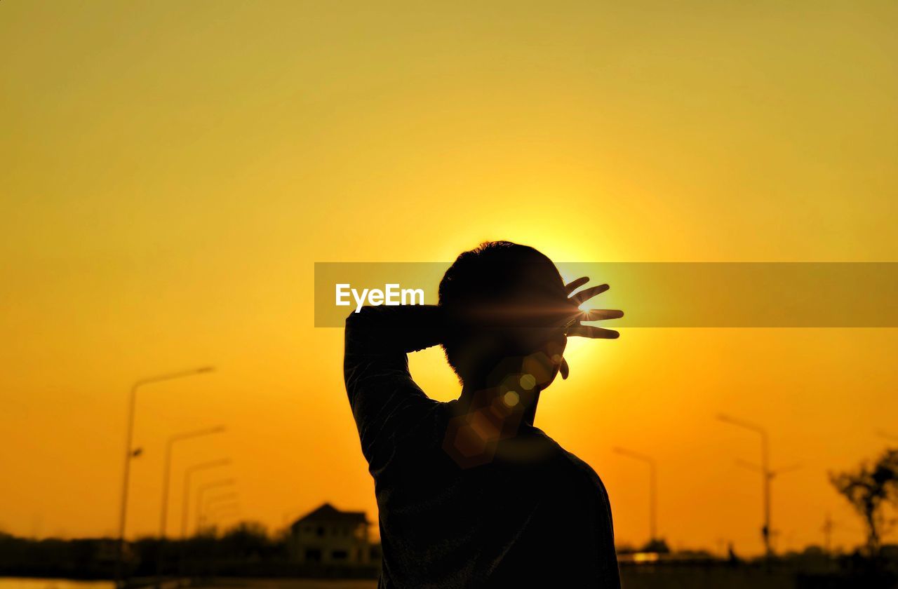 Silhouette man standing against orange sky during sunset