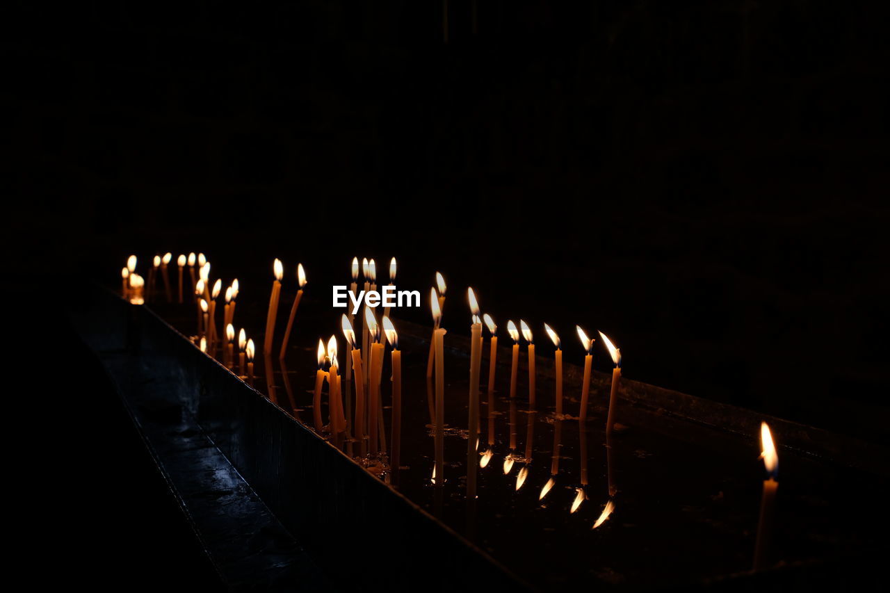 Illuminated candles against black background