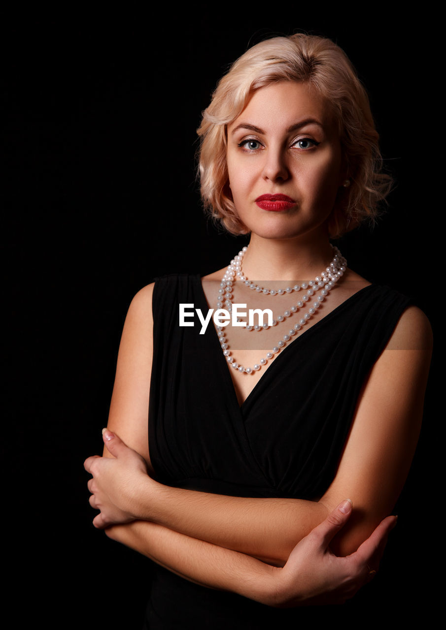 portrait of beautiful young woman against black background