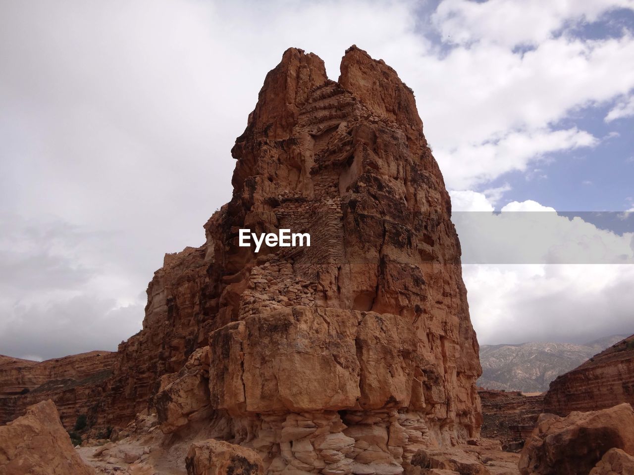 Low angle view of rock formation against cloudy sky