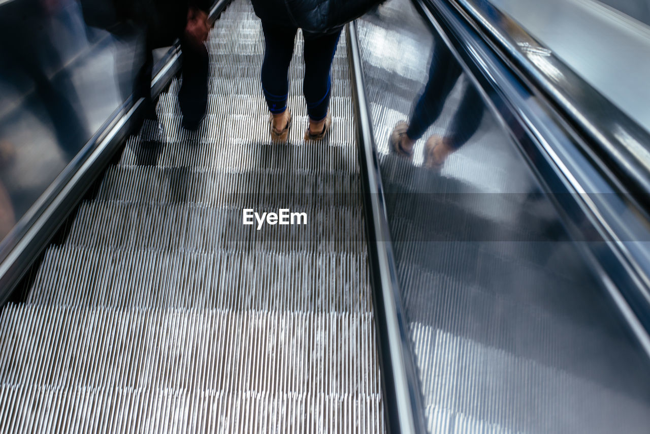 Low section of people standing on escalator