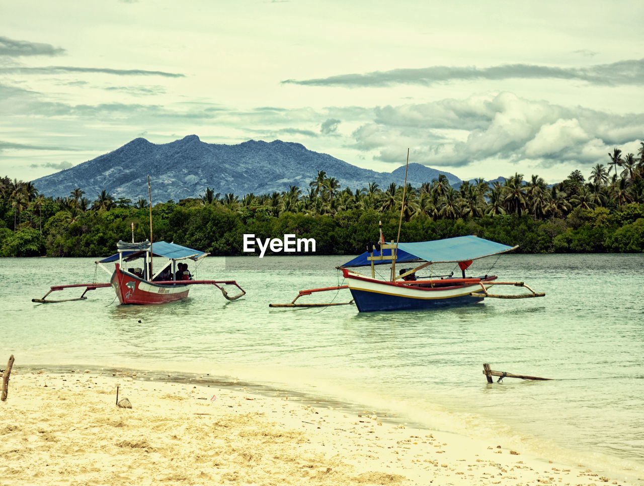 BOATS MOORED ON SHORE AGAINST SKY