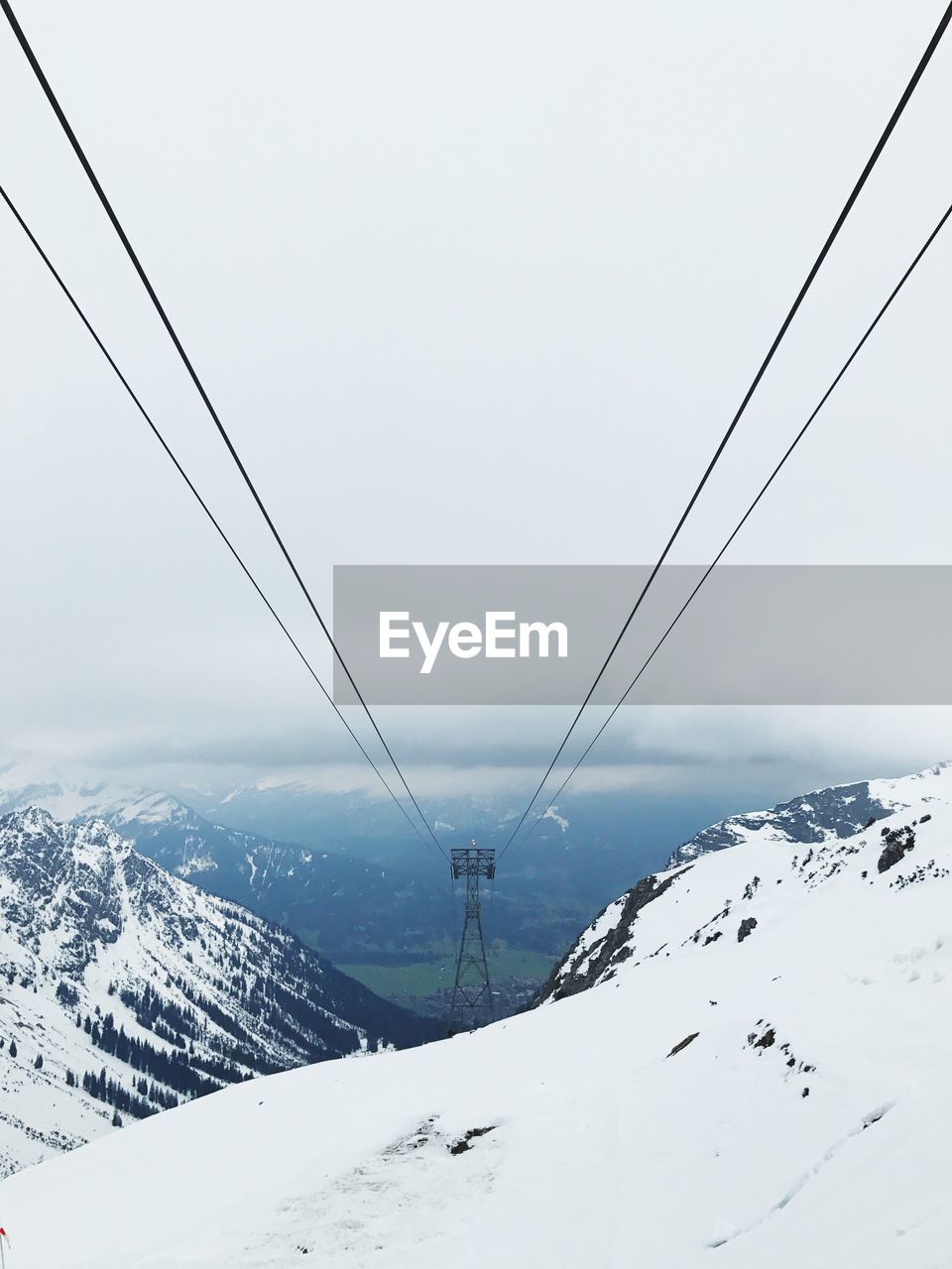 OVERHEAD CABLE CAR OVER SNOW COVERED MOUNTAINS