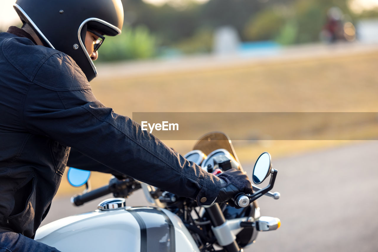 Side view of man riding motorcycle on road