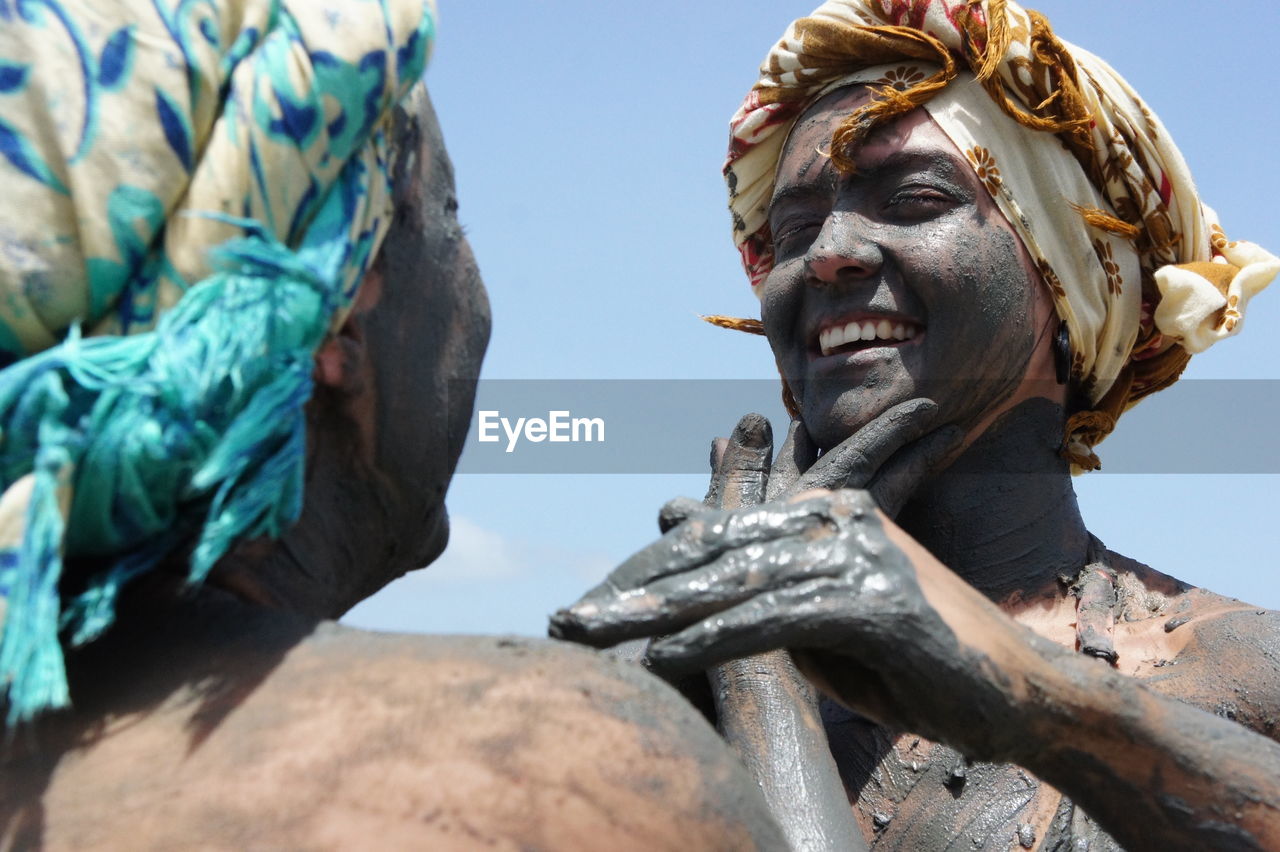 Low angle view of people in mud against blue sky