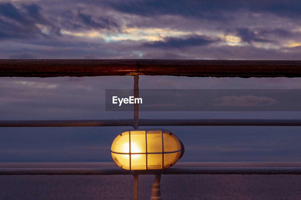 CLOSE-UP OF ILLUMINATED LAMP POST AT SUNSET