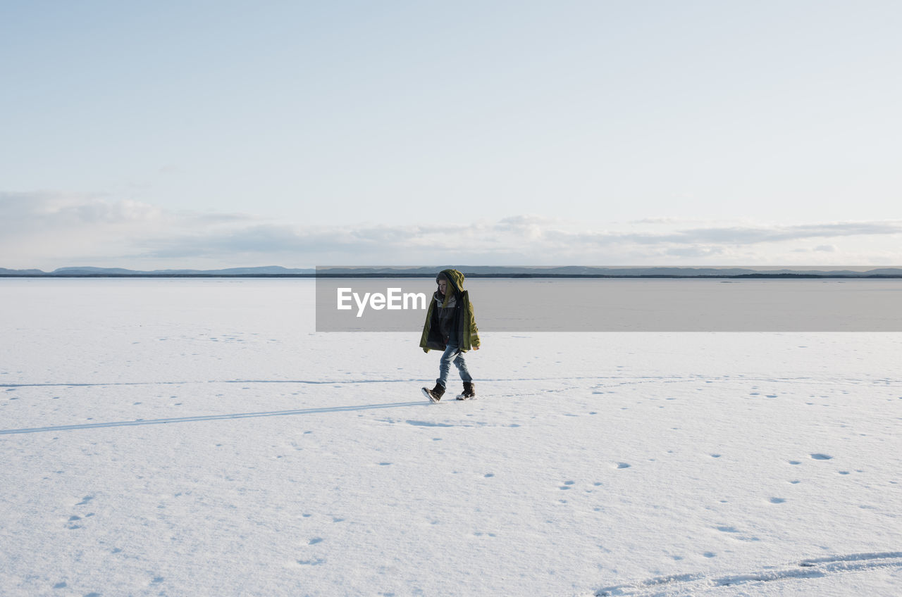 Boy walking across a frozen lake alone in sweden