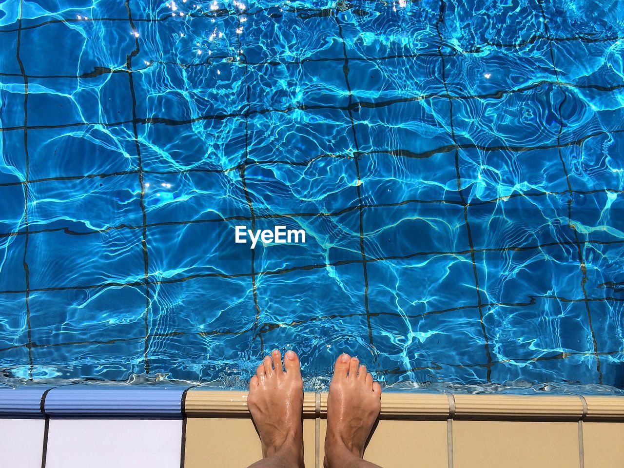 Man's feet standing on edge of swimming pool