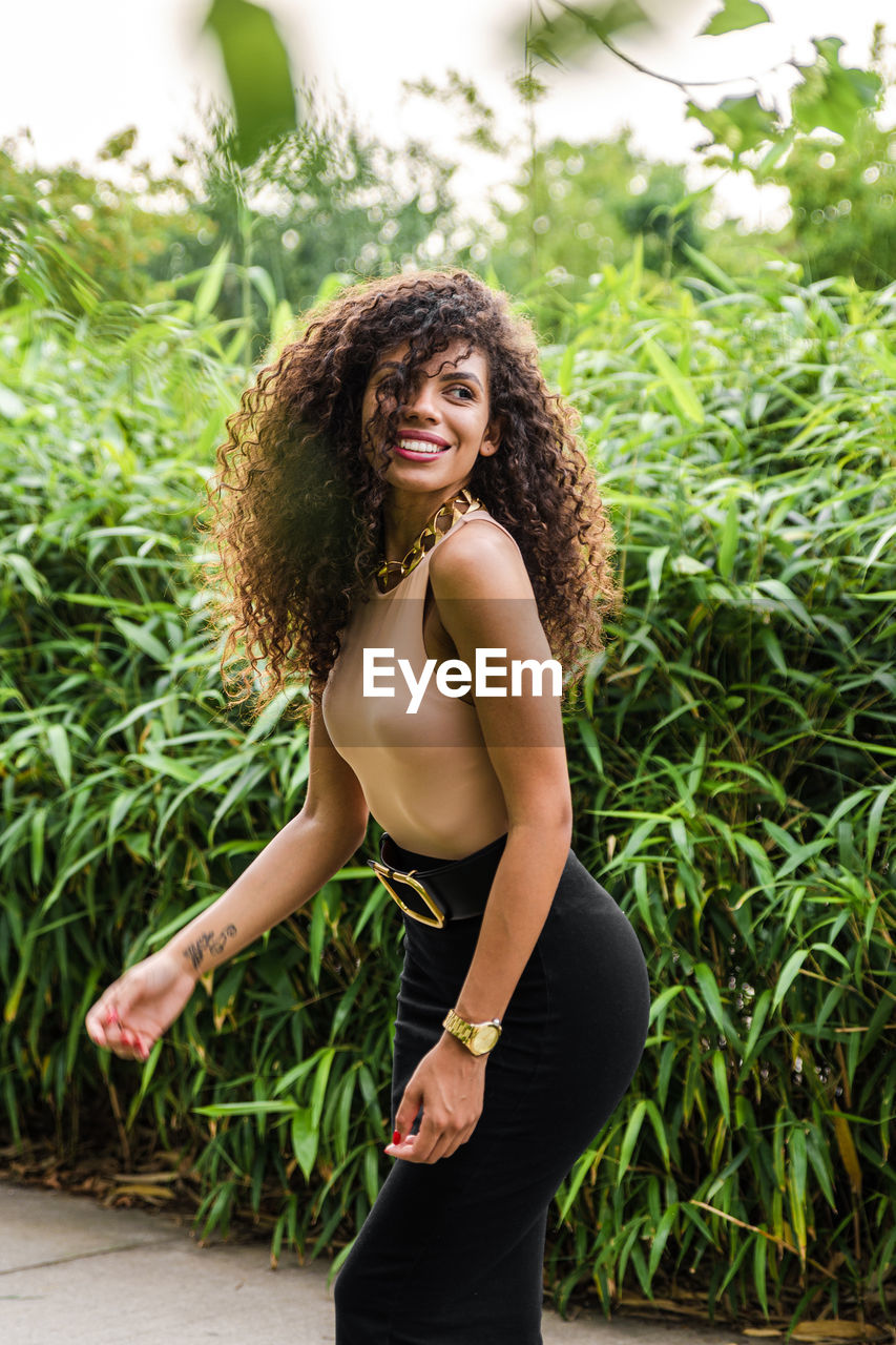 Portrait of young woman standing against plants