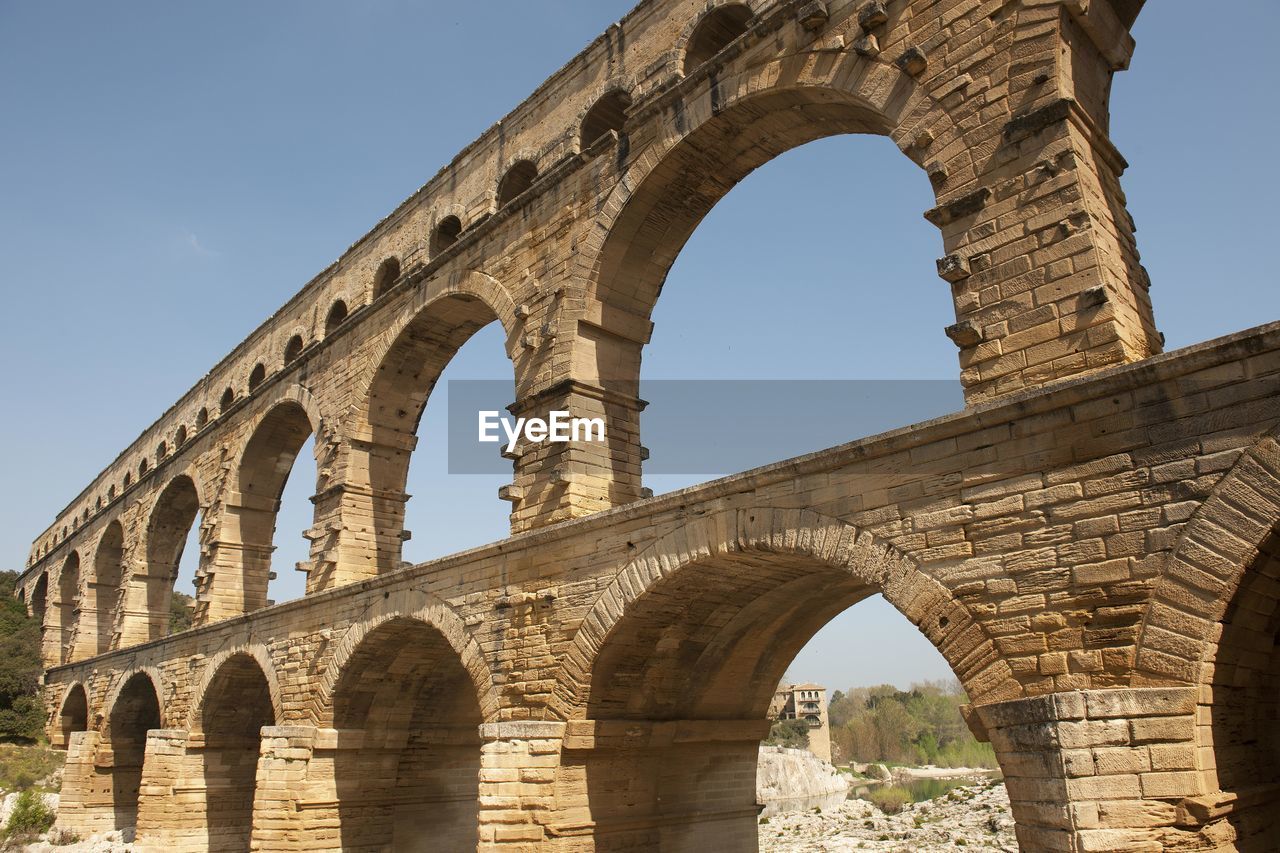 Low angle view of aqueduct against clear blue sky