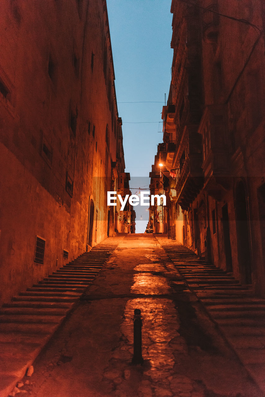 NARROW ALLEY ALONG BUILDINGS AT NIGHT