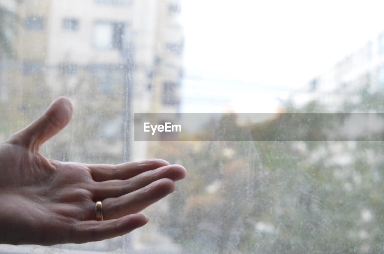 HUMAN HAND ON WET GLASS WINDOW