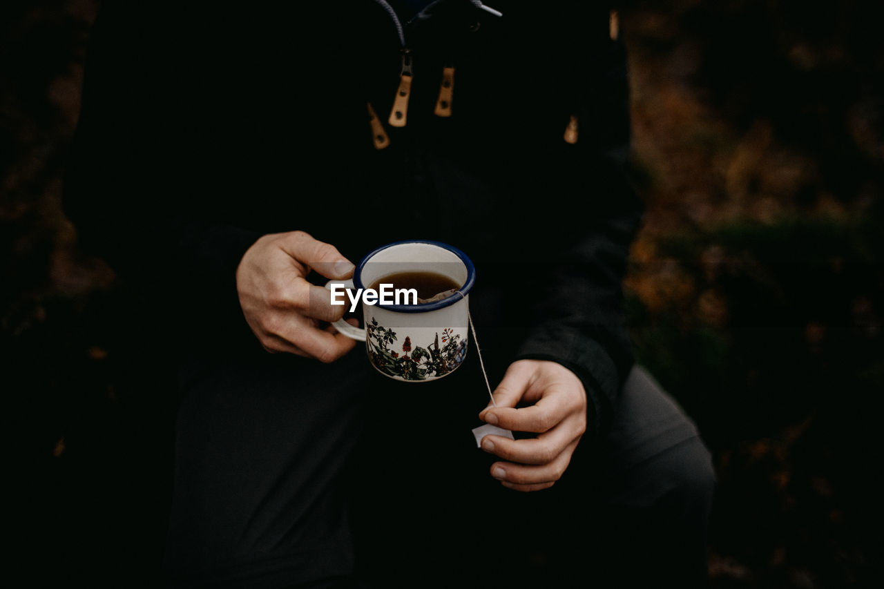 Man holding an enamel mug of tea