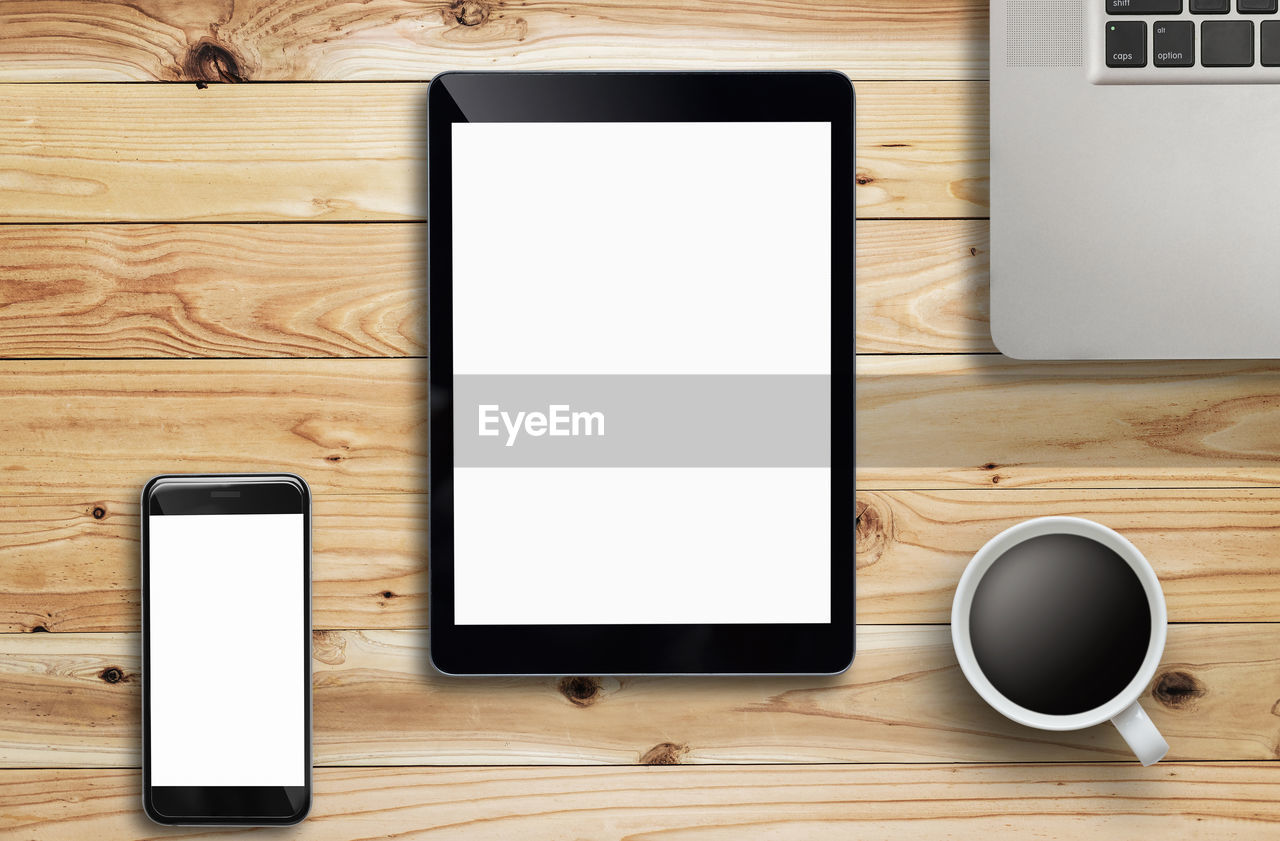 Directly above view of various wireless technology with coffee on wooden table