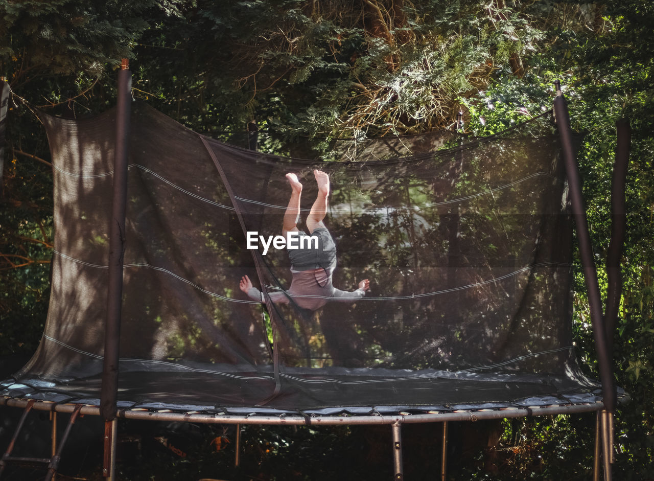 A beautiful caucasian girl in shorts and a sleeved t-shirt jumps on a trampoline