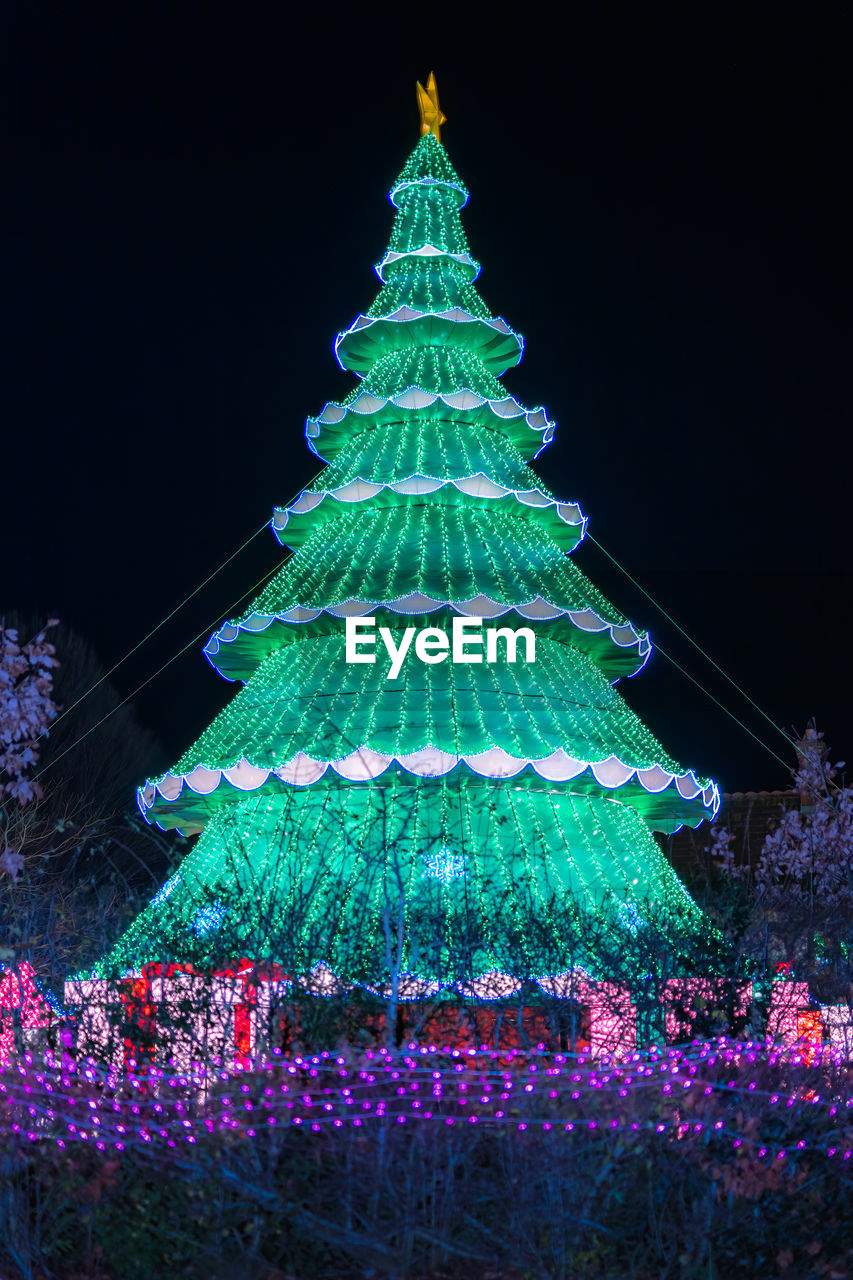 LOW ANGLE VIEW OF ILLUMINATED CHRISTMAS TREE AGAINST SKY