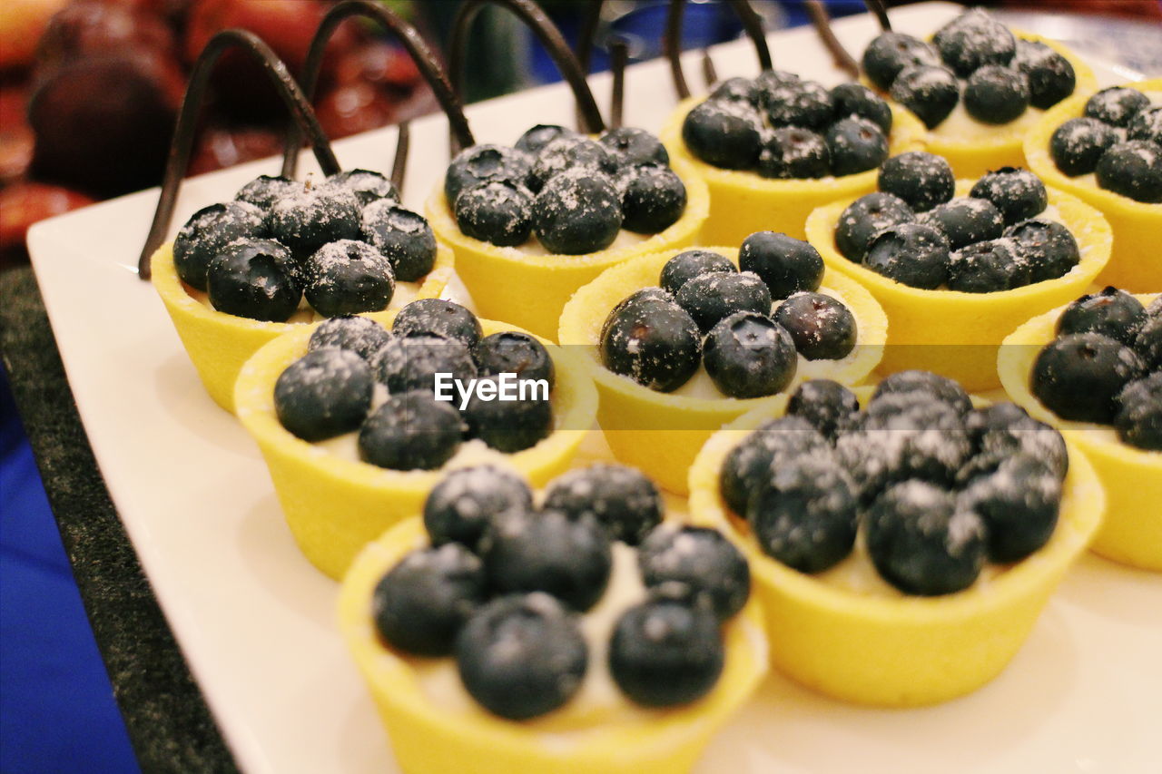 Close-up of blueberry desserts served in yellow bowls on tray