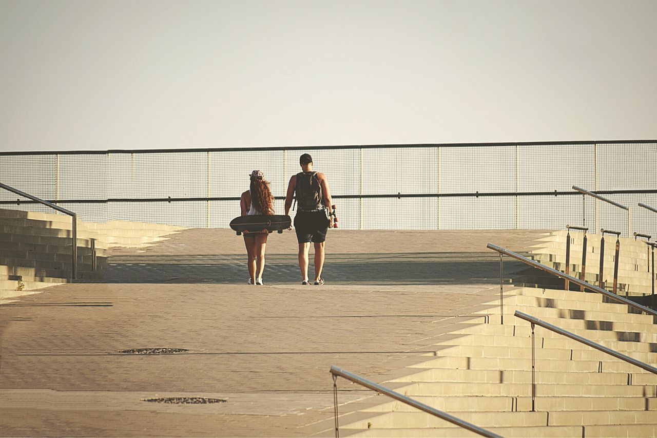 Man and woman with skateboards walking on steps