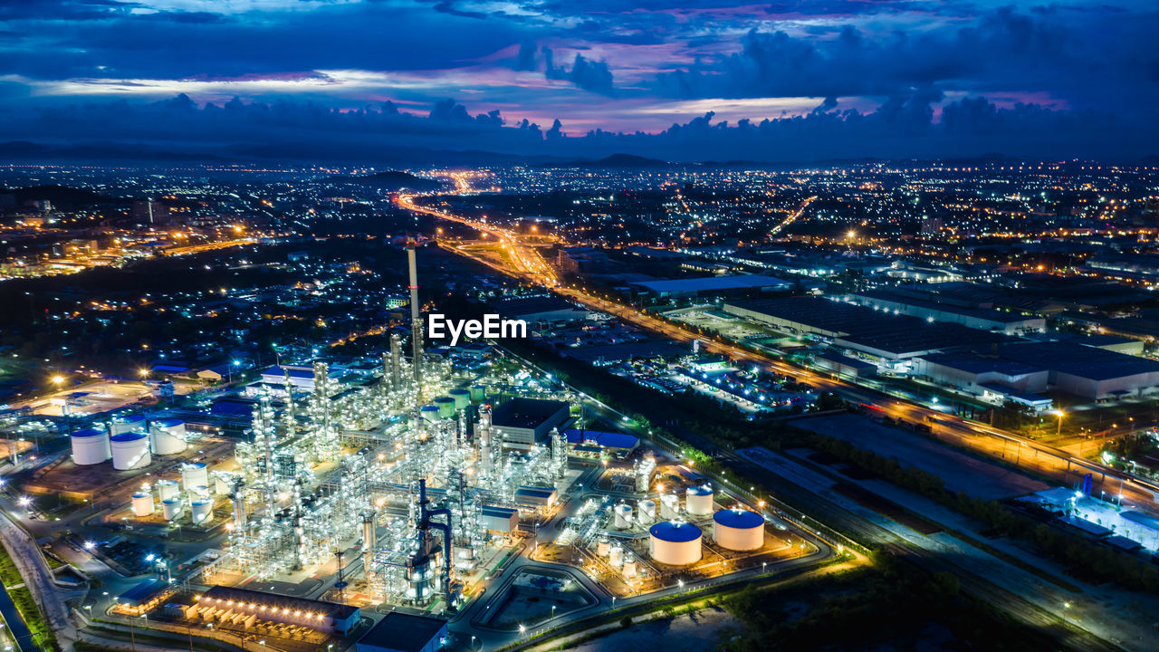 Refinery zone at night and lighting cityscape with blue sky background aerial view from drone