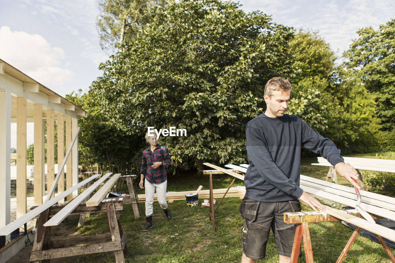 Man with female farm worker making shed against trees